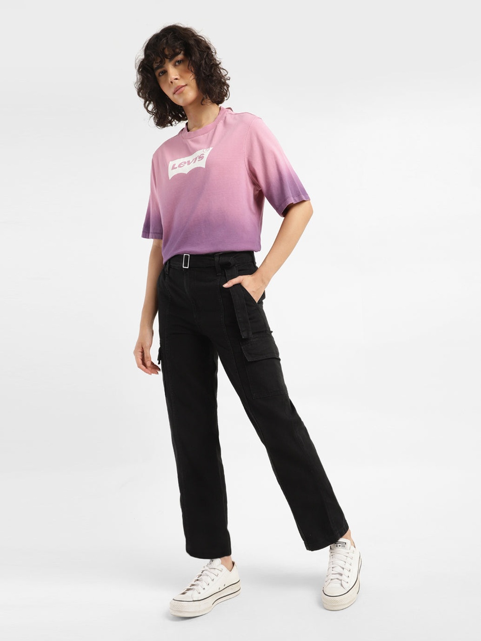 Een jonge vrouw draagt een stijlvol Levi's T-shirt met kleurverloop, een zwarte cargobroek en witte sneakers, een voorbeeld van een casual maar merkgebonden outfit.